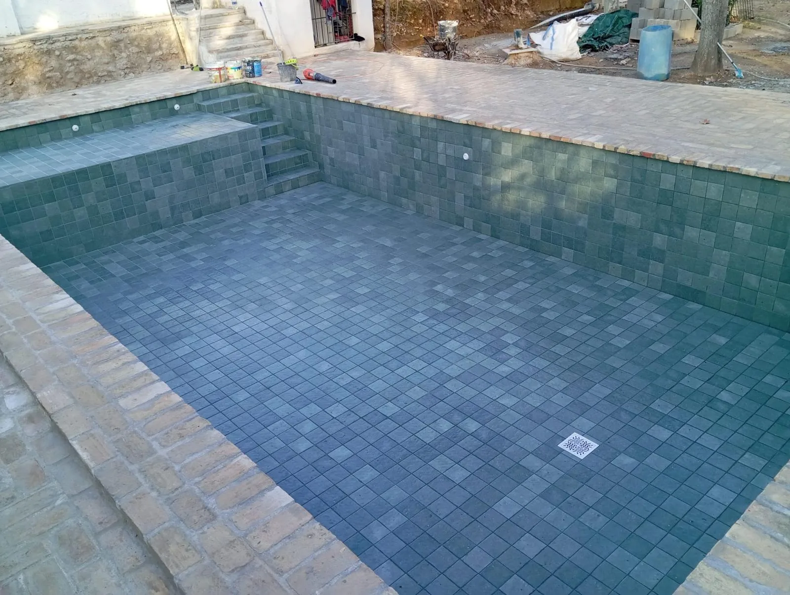 Reforma de piscina con gresite verde y bordillo de ladrillo en Vilamarxant