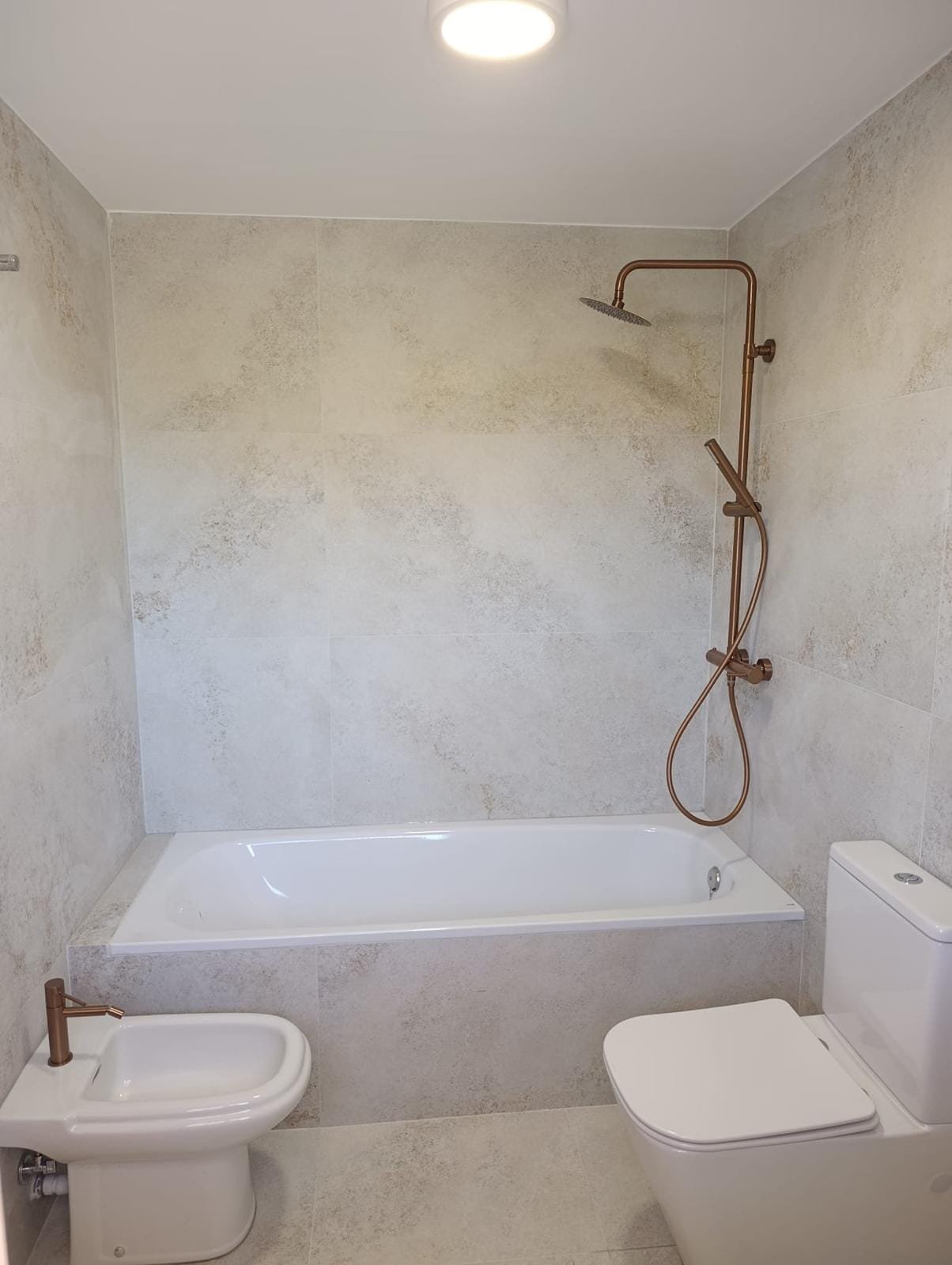 Baño reformado con porcelánico efecto piedra y grifería en cobre en Benaguasil