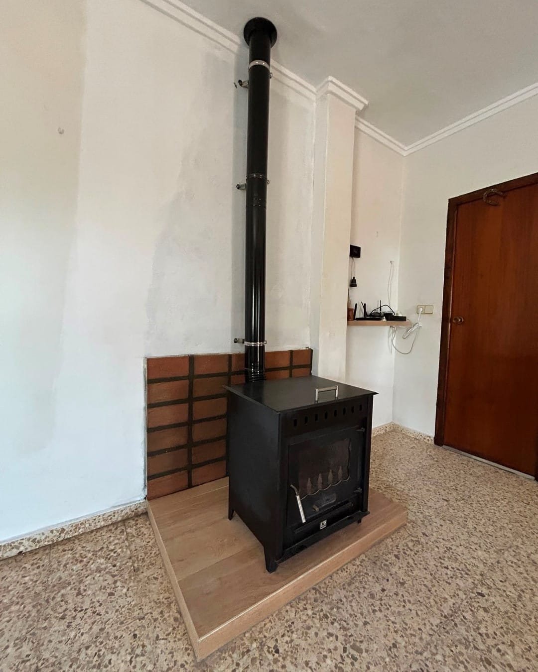 Estufa de leña instalada con ladrillo refractario y escalón de porcelánico en un chalet de Llíria