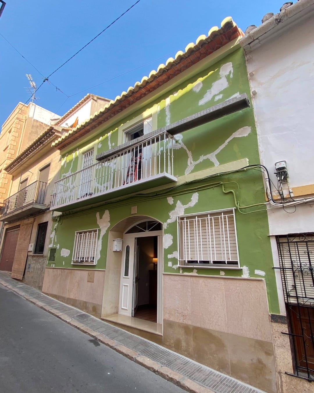 Fachada en el casco antiguo de Llíria con pintura suelta, grietas y parches de masilla antes de repararla